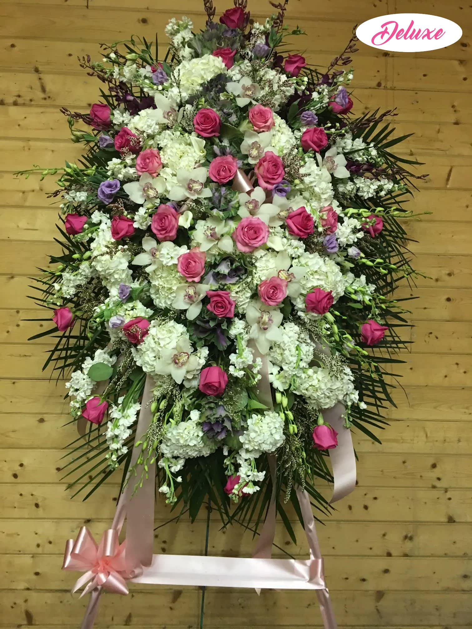 Large standing floral spray with pink roses and white blooms on a ribbon stand