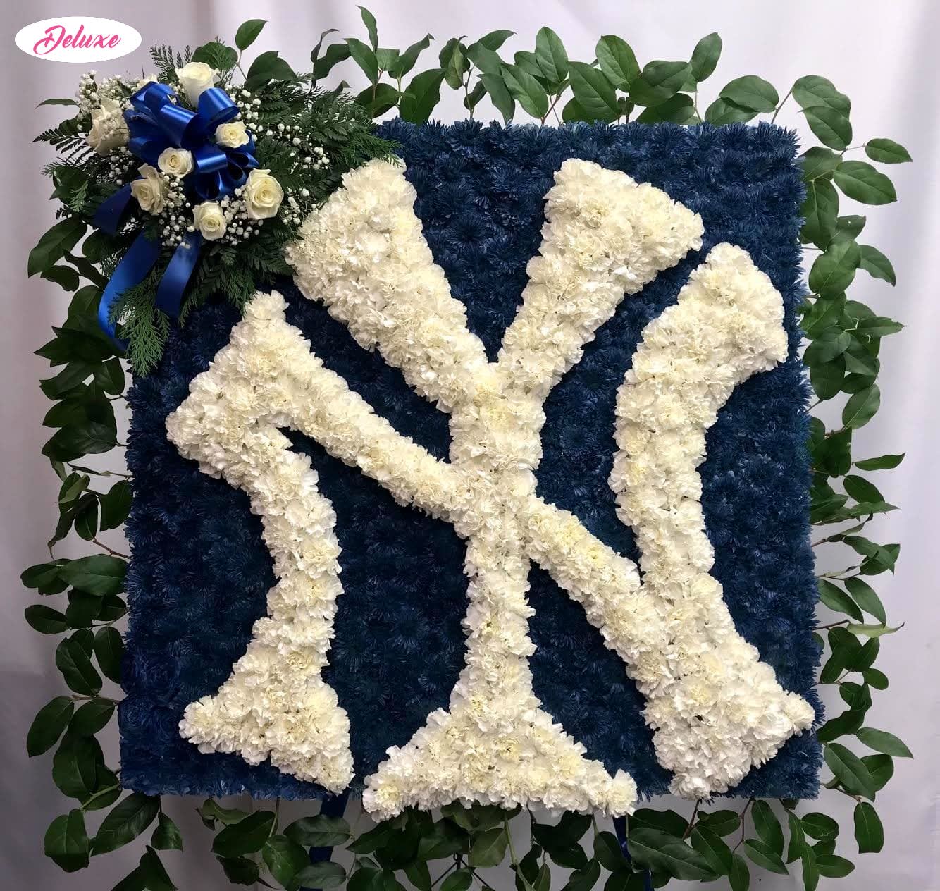 Blue floral tribute with white letter design and a small rose cluster