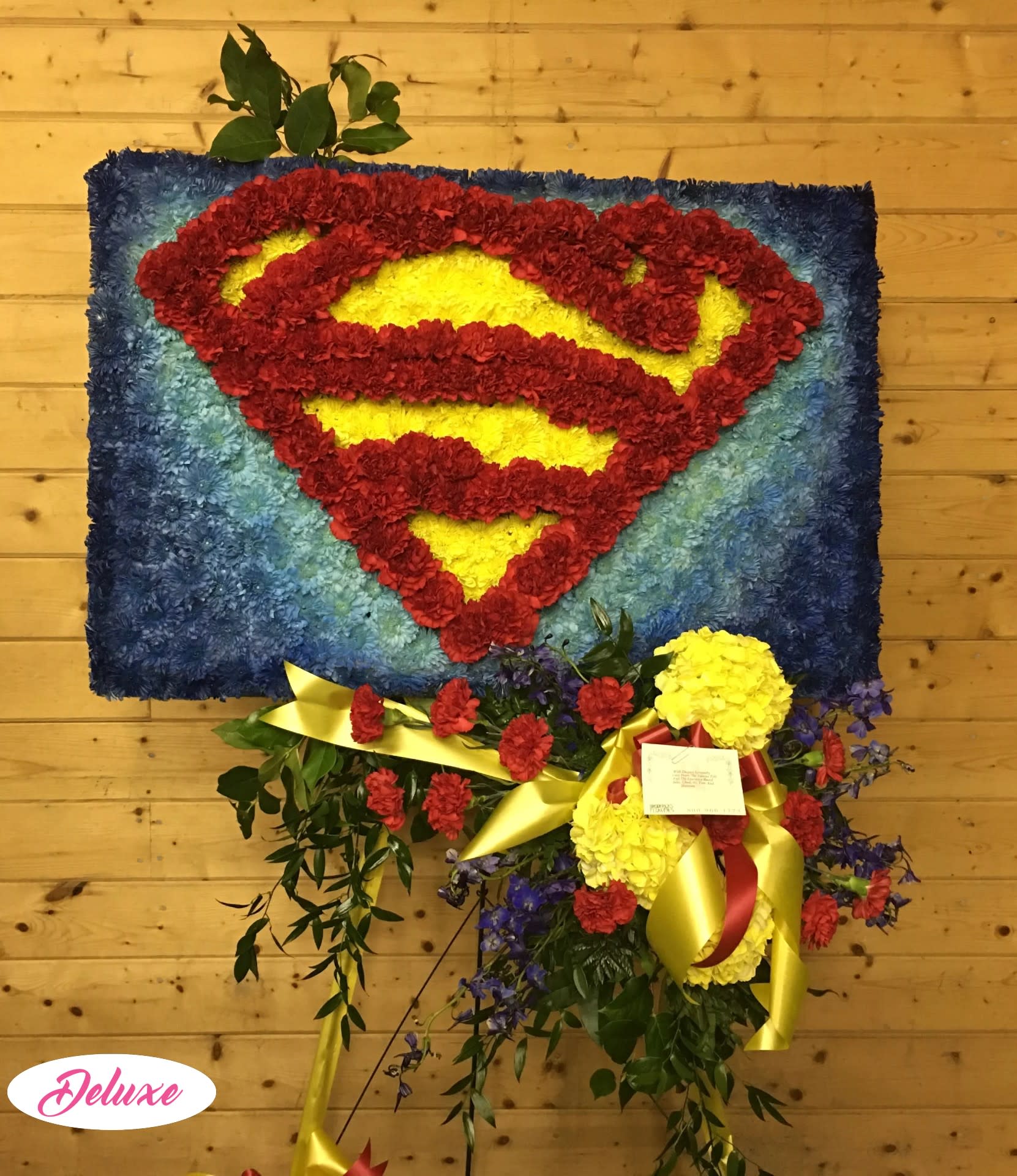 Superman logo made from red and yellow flowers on a blue floral panel
