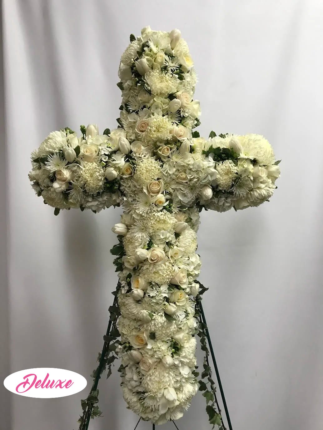 White floral cross arrangement on a stand
