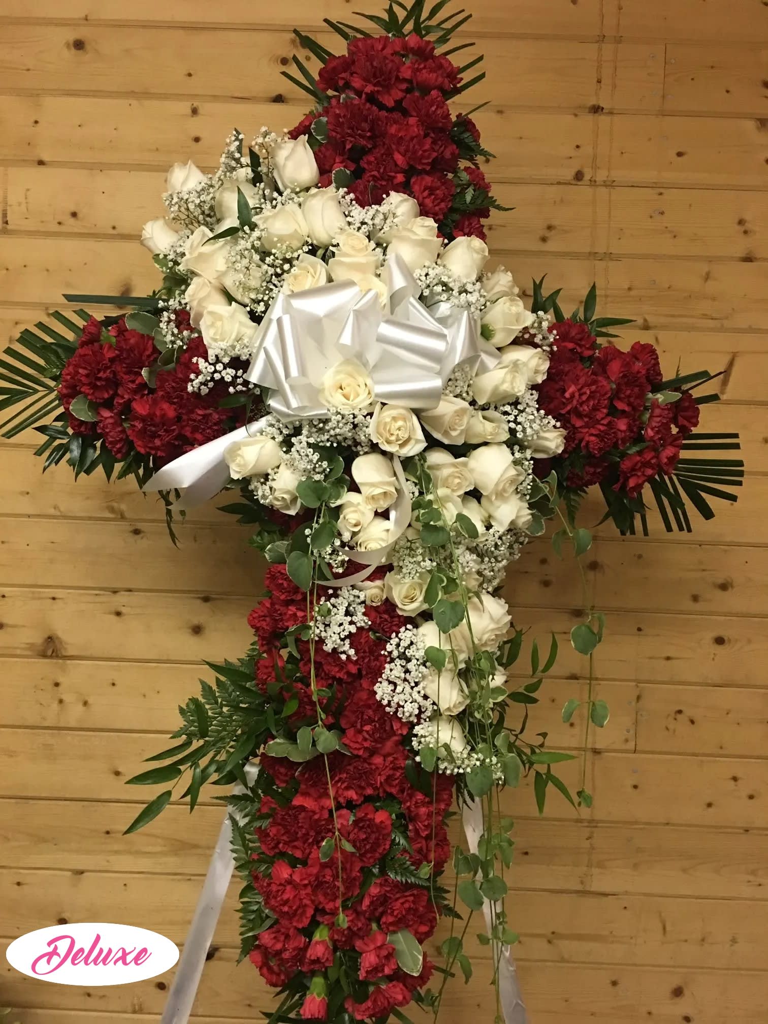 Cross-shaped floral tribute with white roses and red carnations