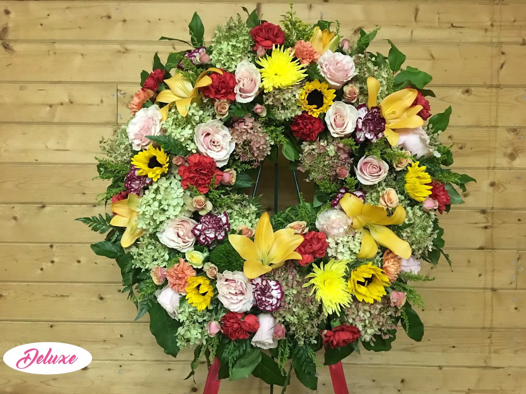 Large circular floral wreath with mixed roses, lilies, and sunflowers