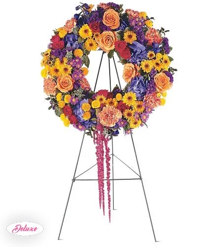 Colorful floral wreath on a standing easel with a pink ribbon tail