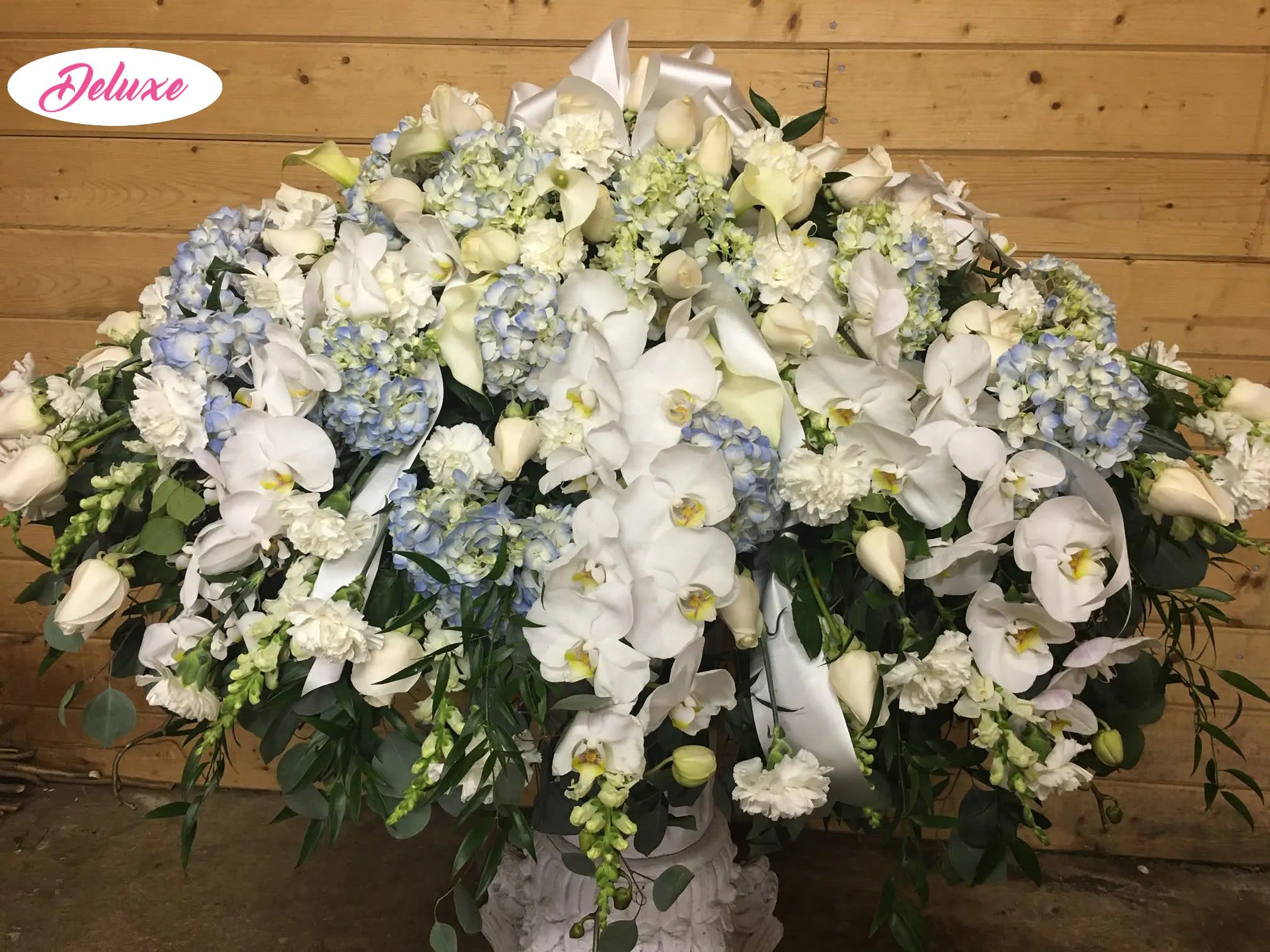 Orchid Elegance  - Orchid Elegance is a graceful casket cover designed to honor and celebrate a cherished life with beauty, love, and respect. This elegant all-white and blue floral arrangement features soft blue hydrangea, classic white roses, delicate white carnations, graceful white phalaenopsis orchids, and elegant white snapdragons, thoughtfully arranged to create a peaceful and sophisticated tribute. The serene color palette symbolizes remembrance, sympathy, and heartfelt devotion, offering a meaningful expression of love and support during a difficult time. Handcrafted by our compassionate florists, Orchid Elegance is a timeless floral tribute created to bring comfort and honor a beautiful memory.