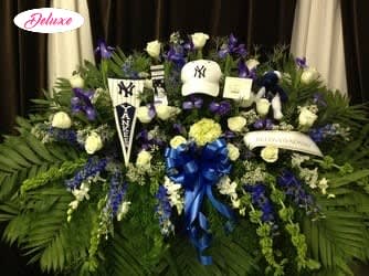 Large funeral spray with white roses, purple flowers, and a blue ribbon