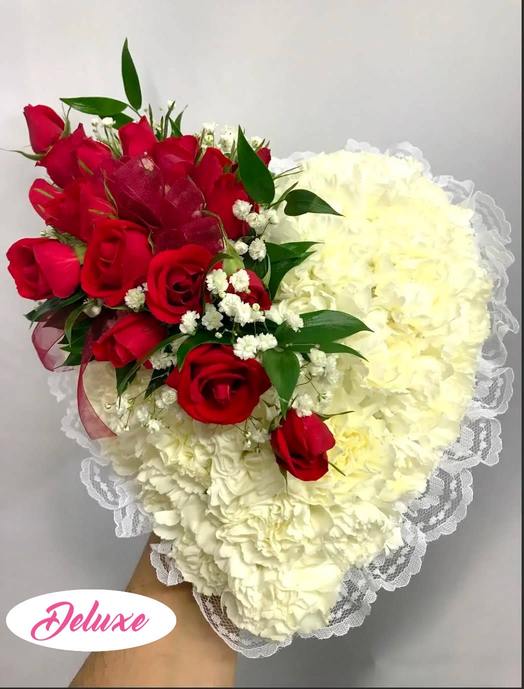 Heart-shaped bouquet of red roses and white carnations with lace trim