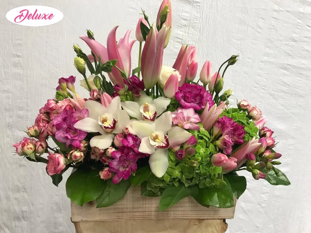 Pink lilies, white orchids, and magenta flowers in a wooden box