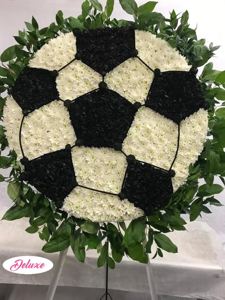Soccer ball floral tribute on a stand with white and black flowers