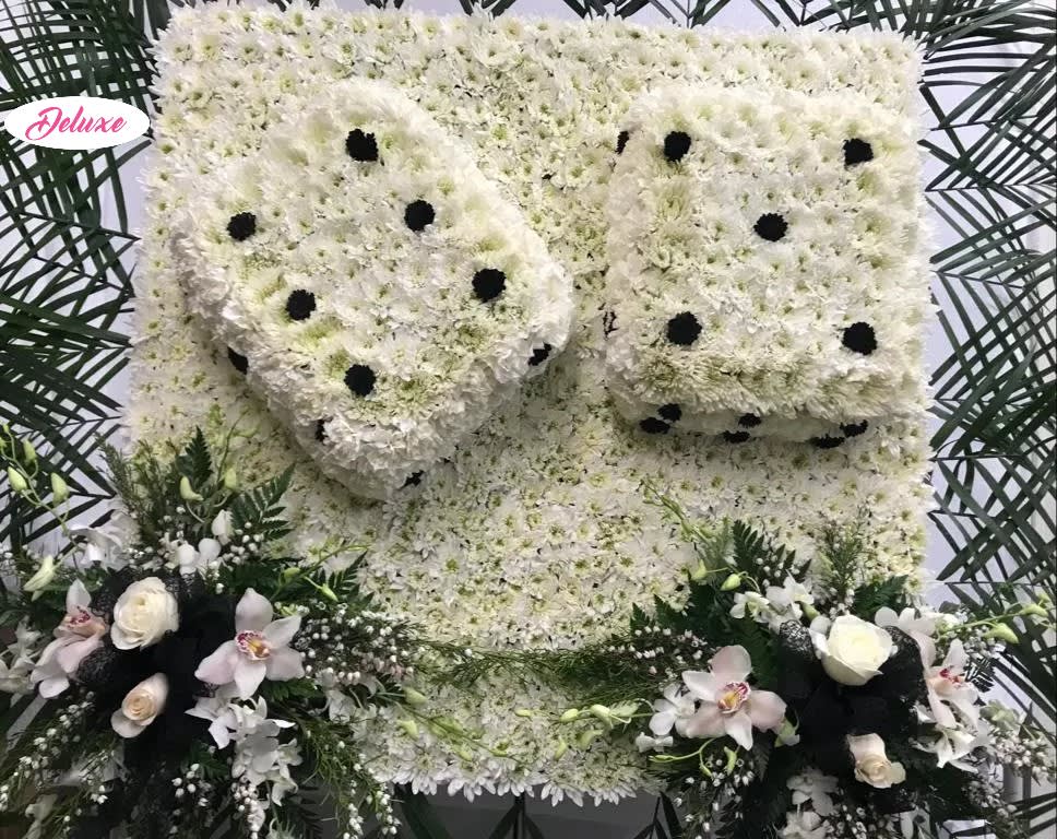 Large white floral funeral tribute with black dot accents and orchid sprays