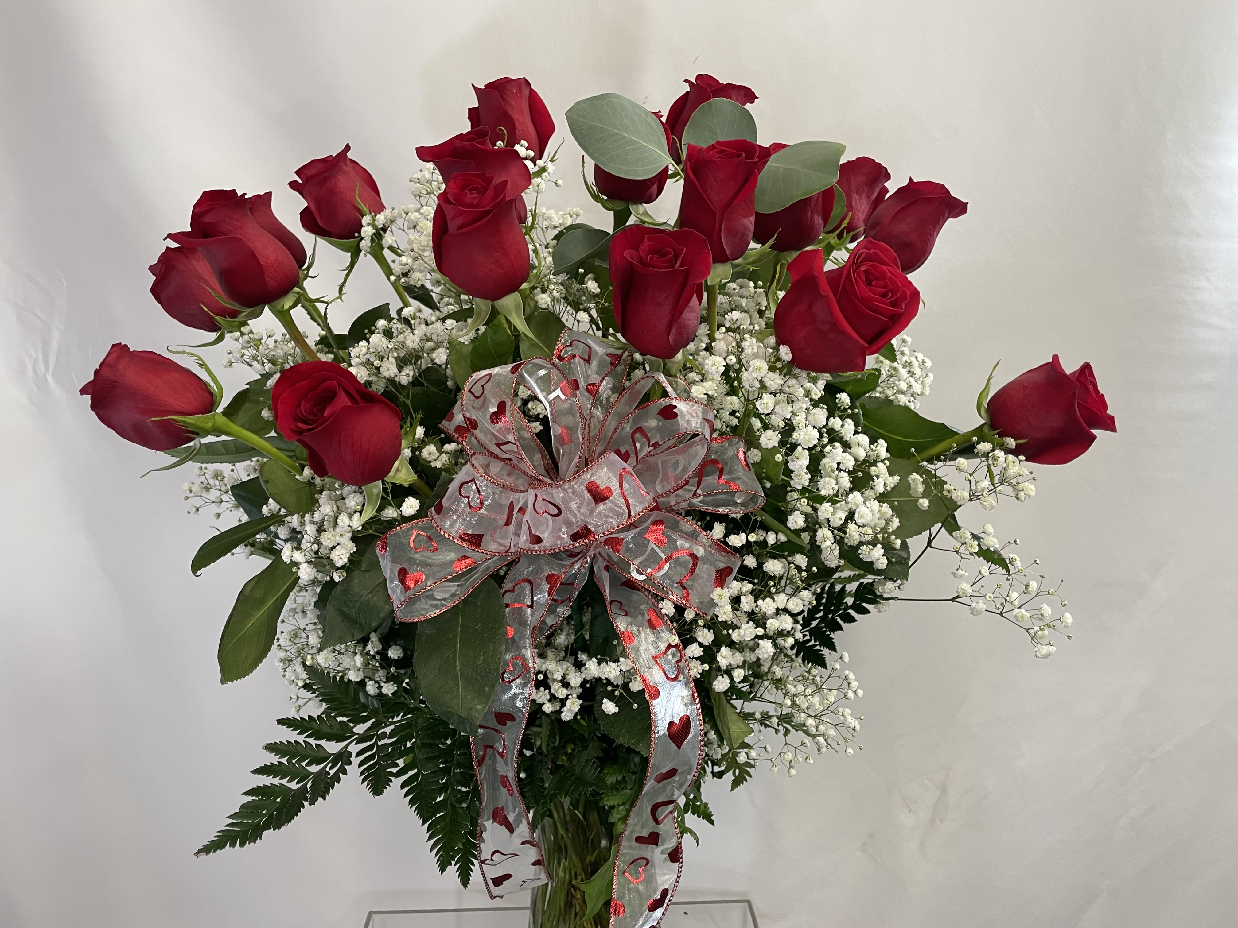 Bouquet of red roses with baby's breath and a heart-patterned ribbon