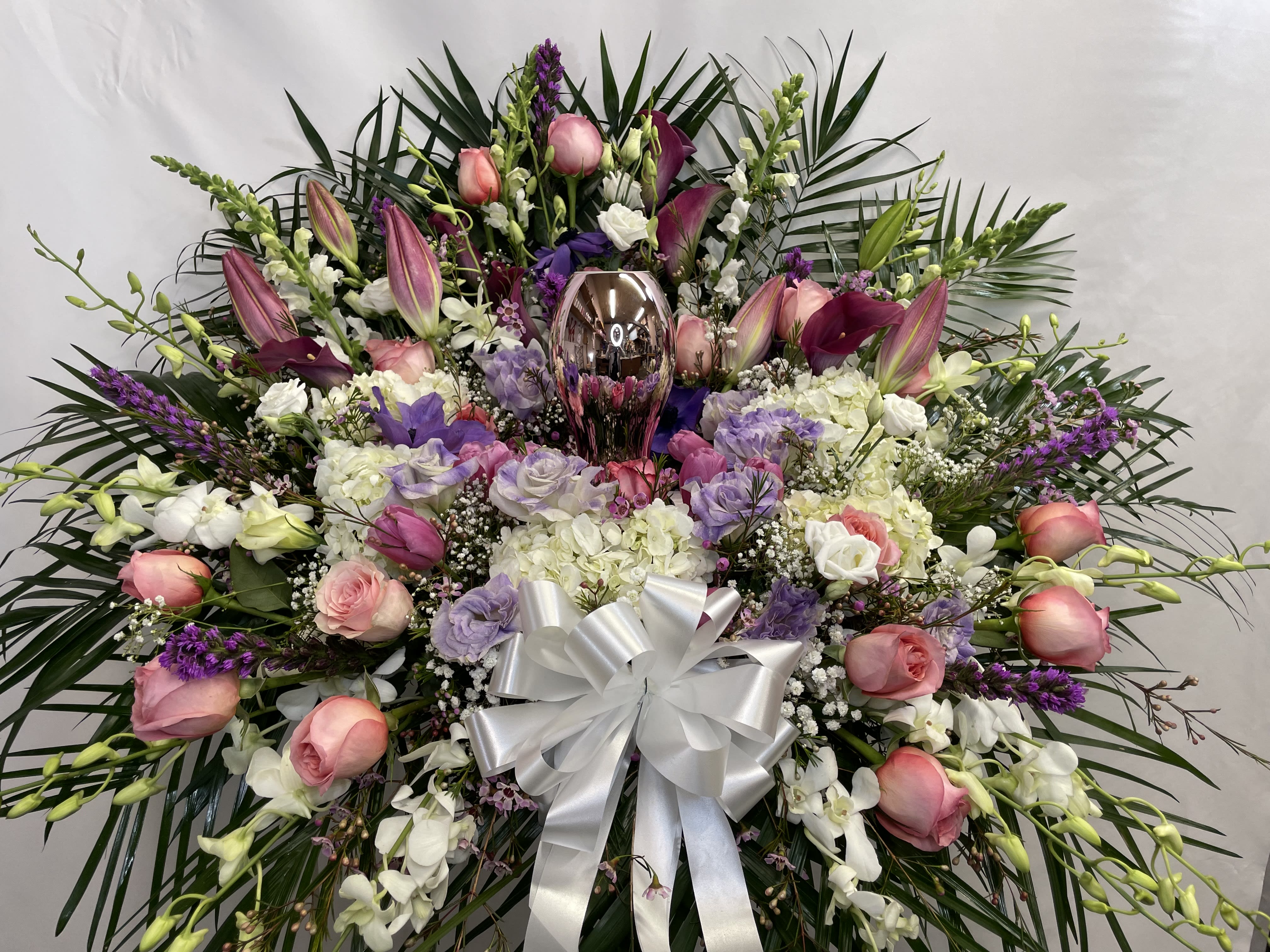 Large floral spray with pink roses, white orchids, and a silver bow