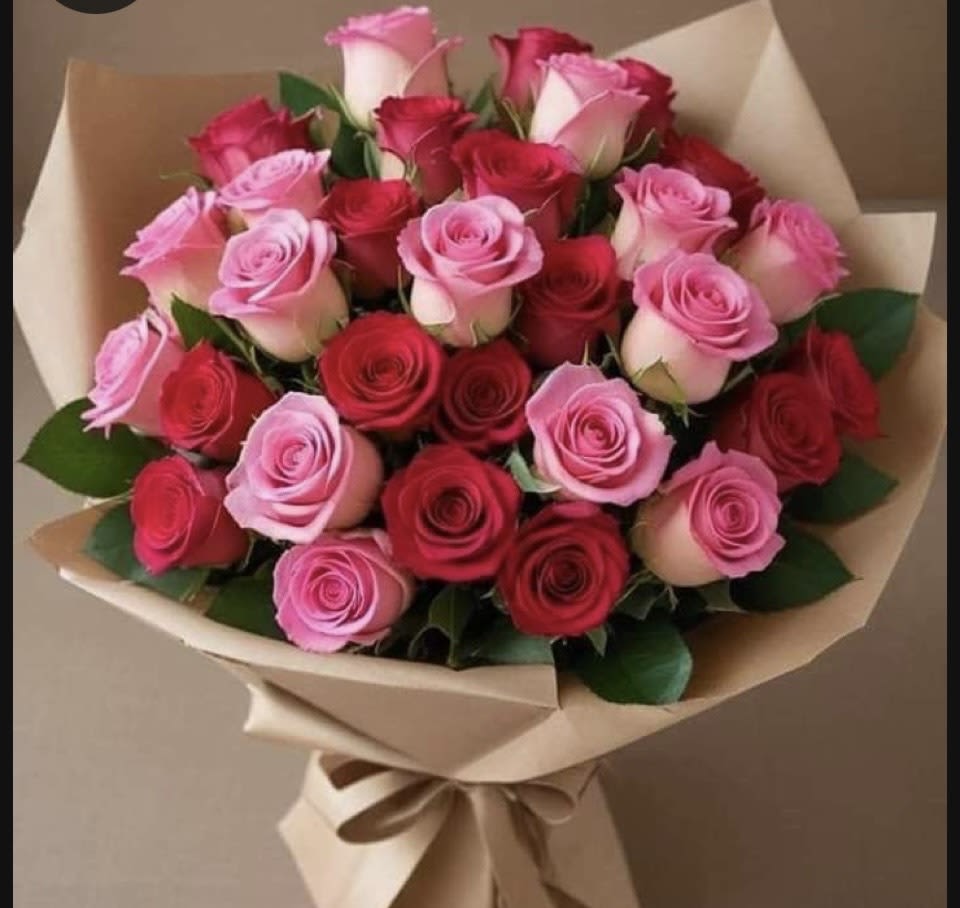 Large bouquet of red and pink roses wrapped in tan paper with a tied ribbon