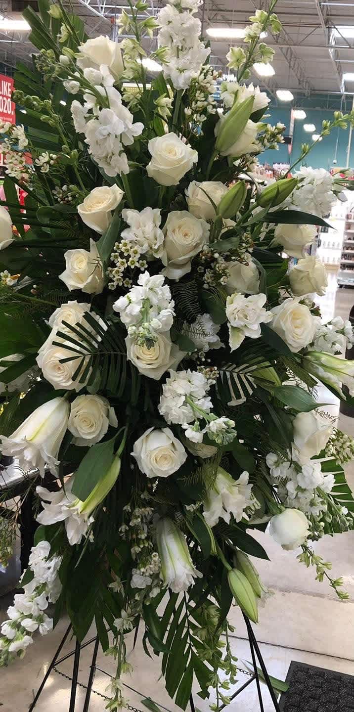 Large white floral standing spray with roses and lilies on an easel