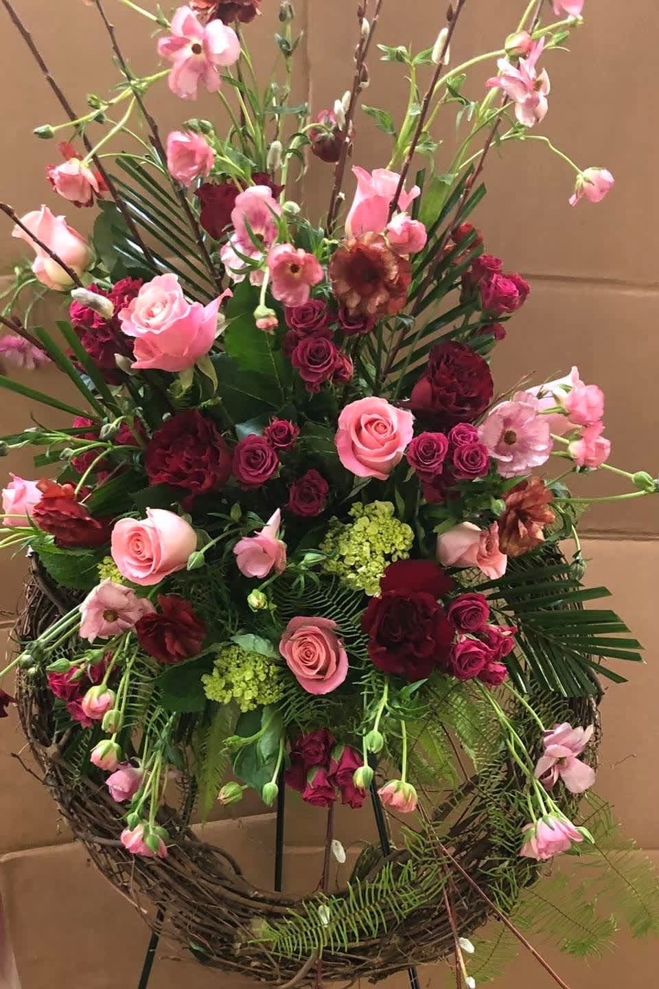 Large pink and burgundy floral arrangement in a wicker stand
