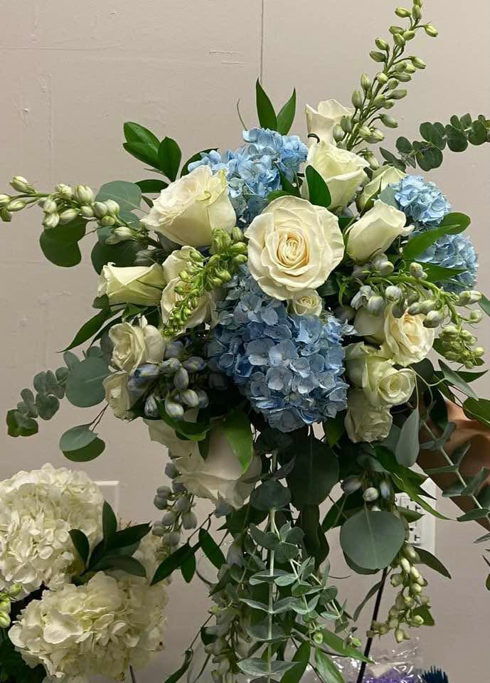 Bouquet of white roses and blue hydrangeas with mixed greenery