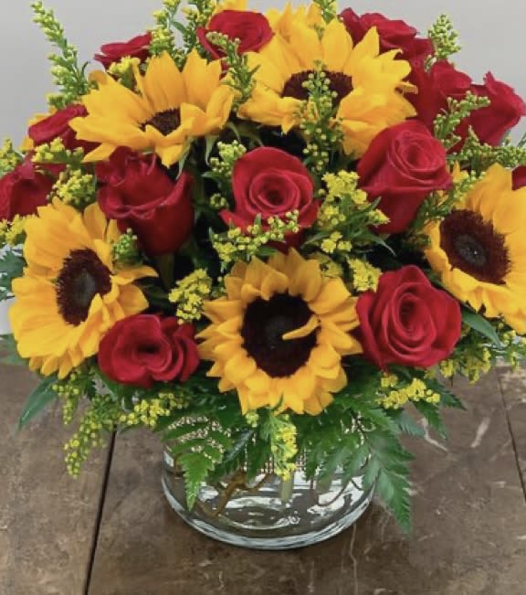 Bouquet of red roses and yellow sunflowers in a glass vase