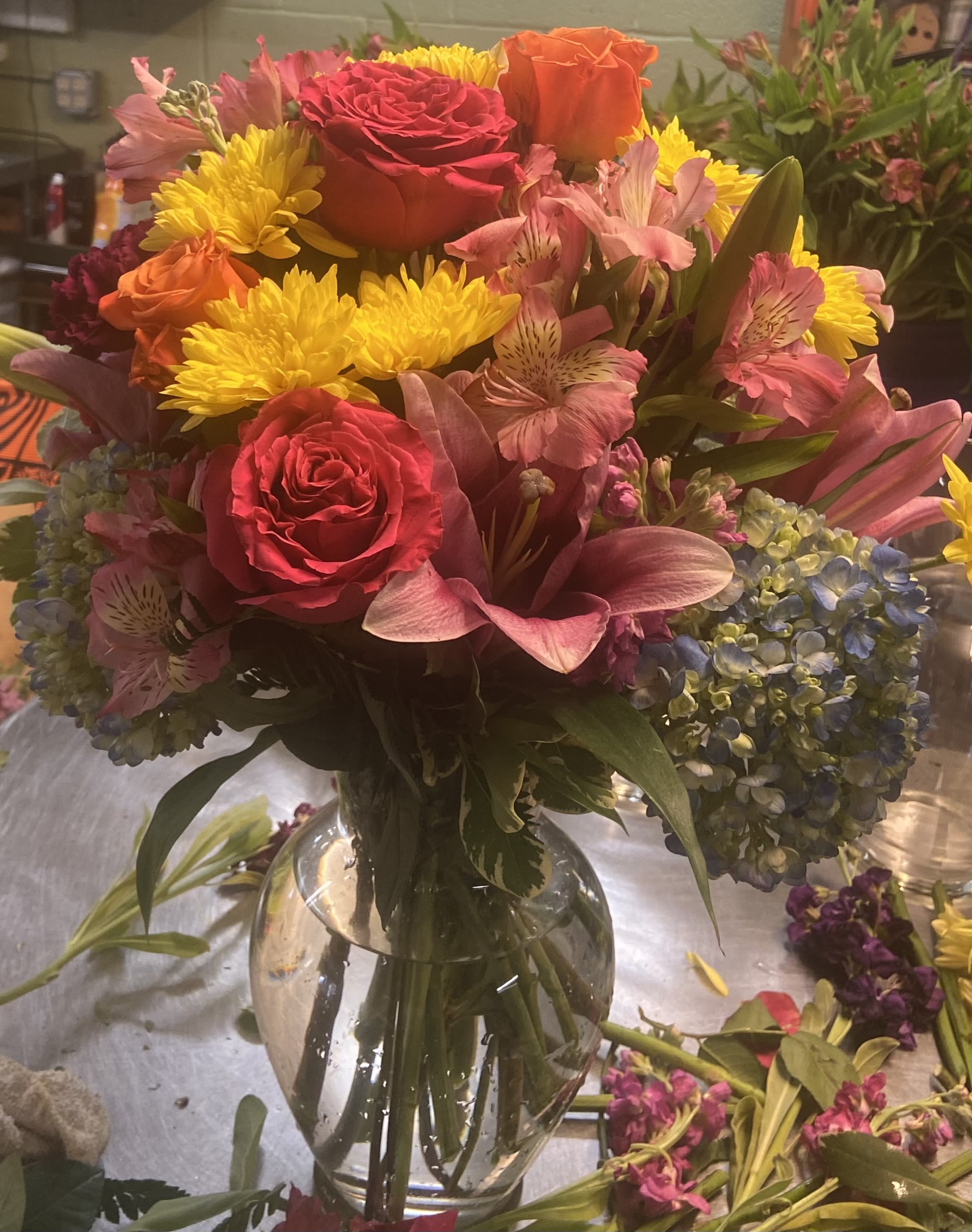 Mixed bouquet of roses, lilies, chrysanthemums, and hydrangeas in a glass vase