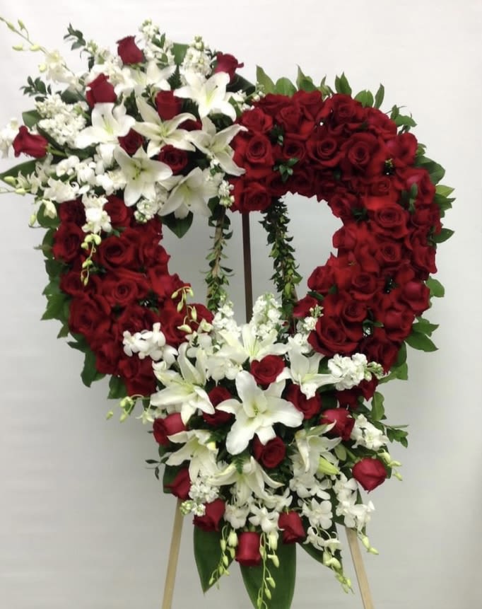 Heart-shaped standing spray of red roses and white lilies on an easel
