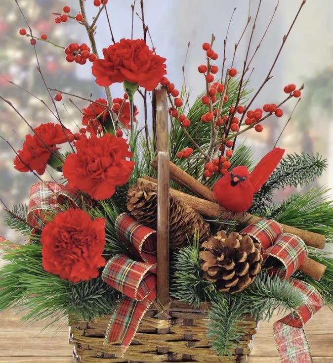 Red carnations in a basket with pinecones, plaid ribbon, and a red cardinal ornament