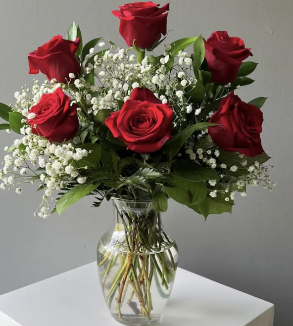 Red roses and baby's breath arranged in a clear glass vase