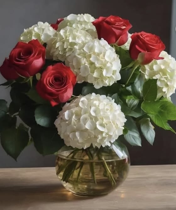 Red roses and white hydrangeas in a round glass vase