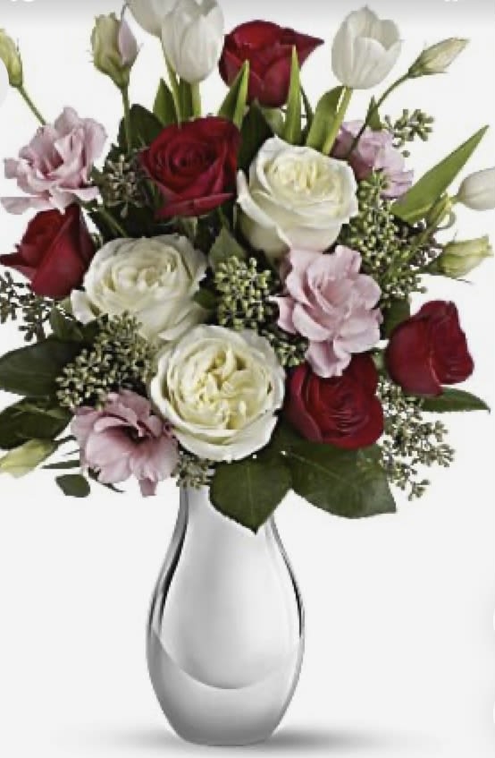 Bouquet of red, white, and pale pink roses in a white vase