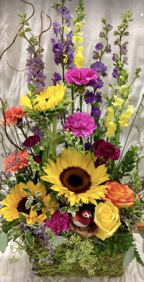 Tall mixed flower arrangement with sunflowers, roses, and purple blooms in a basket