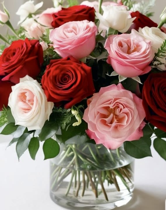 Bouquet of red, pink, and white roses in a clear glass vase