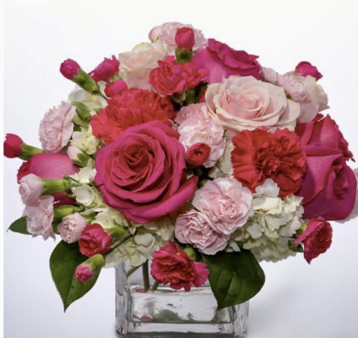 Pink and white roses with carnations in a clear glass vase