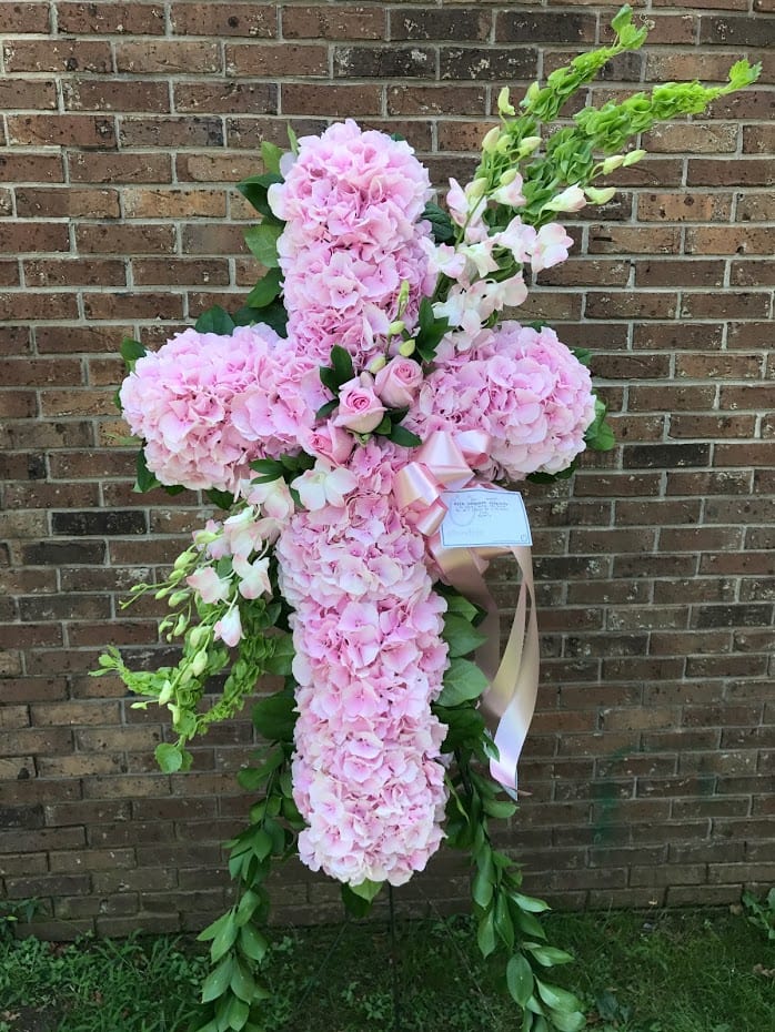 Standing cross of pink hydrangeas with pink roses and green bells of Ireland on an easel.