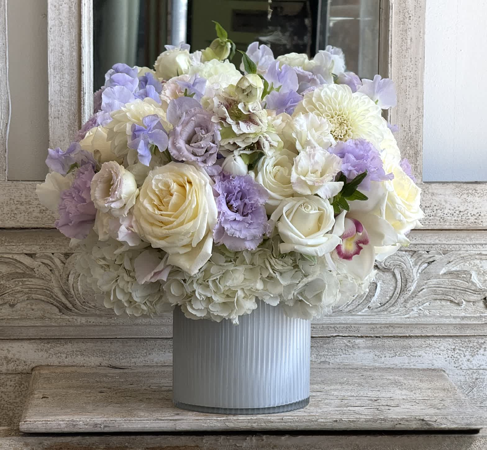 Pastel bouquet of white and lavender flowers in a ribbed vase