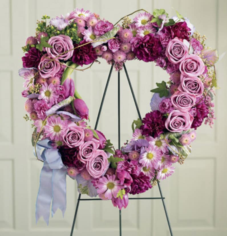 Heart-shaped floral wreath with pink and purple flowers on a stand