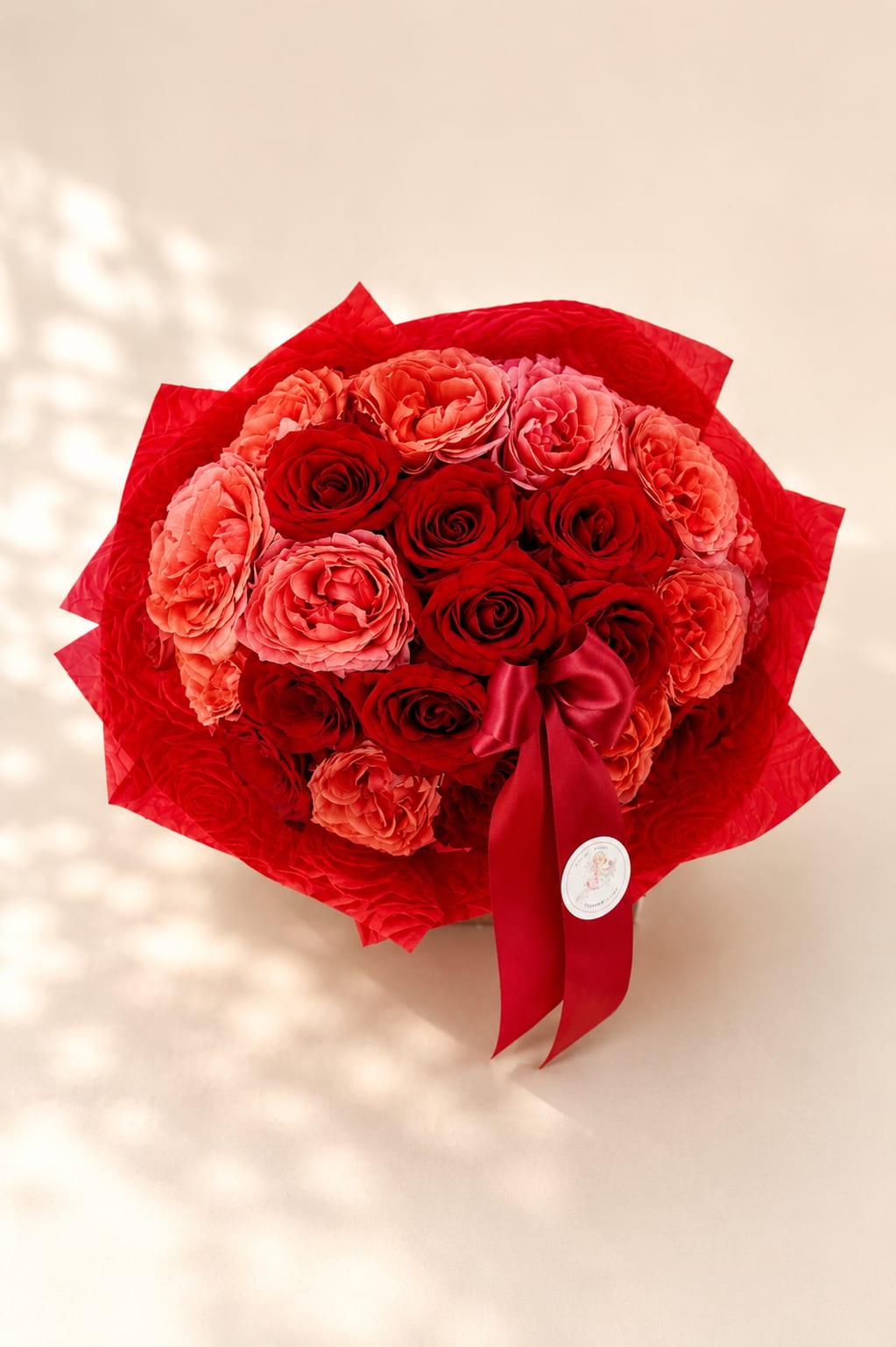 Amor's Crimson Embrace – Luxury Two Dozen Rose Bouquet - Inspired by Amor, the Roman god of love, this bouquet celebrates romance through timeless beauty and elegant design.  Amor's Crimson Embrace features two dozen premium roses in a rich blend of classic red and warm coral tones. Wrapped in luxurious waterproof designer paper and finished with a satin ribbon, this bouquet combines vibrant color, lush garden-style blooms, and refined presentation to create an unforgettable gift.  Perfect for anniversaries, Valentine's Day, birthdays, romantic surprises, proposals, or simply expressing love and appreciation. Its bold yet sophisticated color palette makes it a beautiful choice for any meaningful celebration.  Each bouquet is handcrafted by Flower Fairy using the freshest roses available. While occasional substitutions may be necessary due to seasonal availability, we always preserve the overall style, color palette, and premium quality of every design.  Features: Two dozen premium roses Red and coral roses Luxury wrapped bouquet Waterproof designer wrapping Satin ribbon finish Handcrafted by Flower Fairy Same-day flower delivery in Phoenix