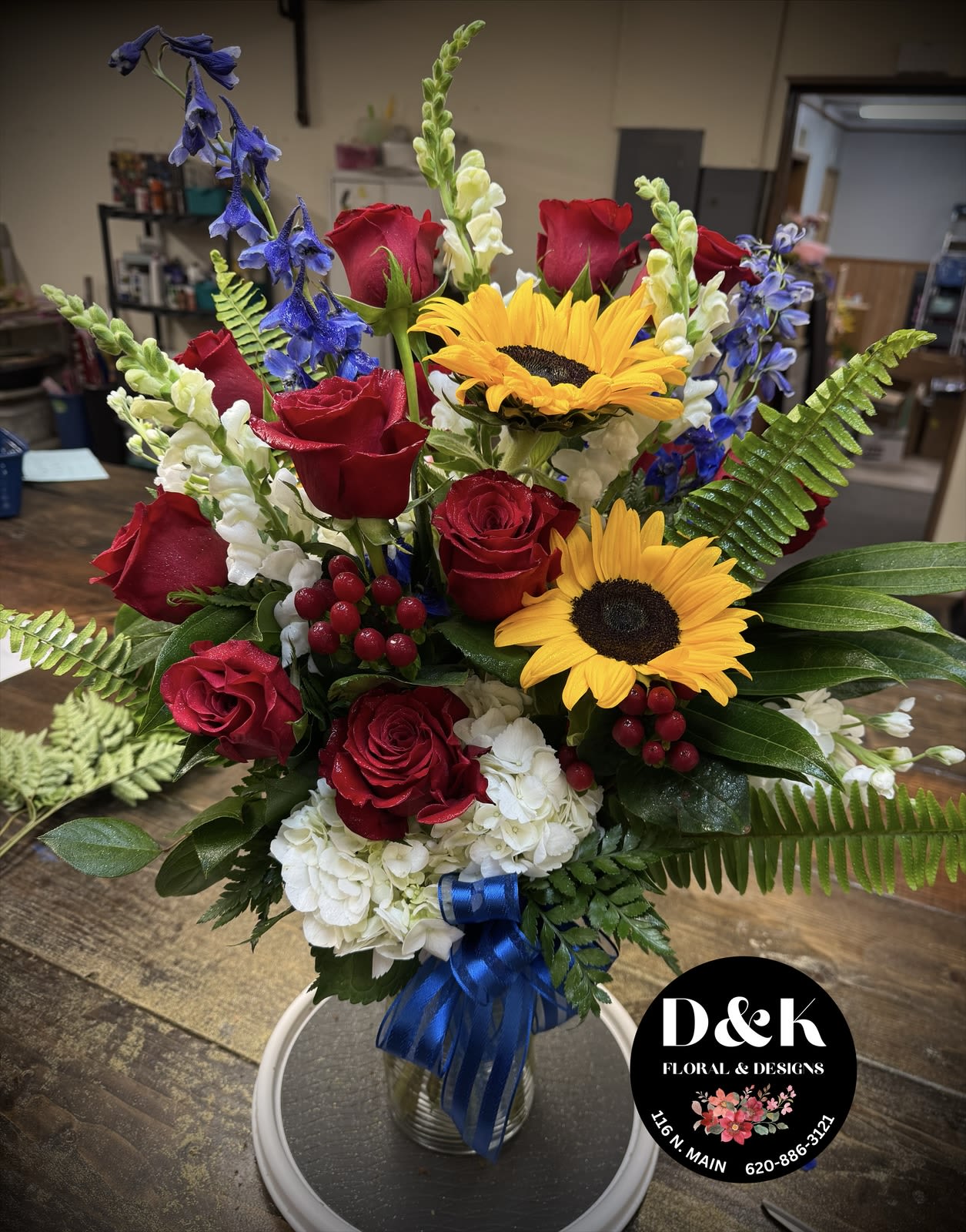 Bouquet of red roses, sunflowers, and white hydrangeas in a glass vase