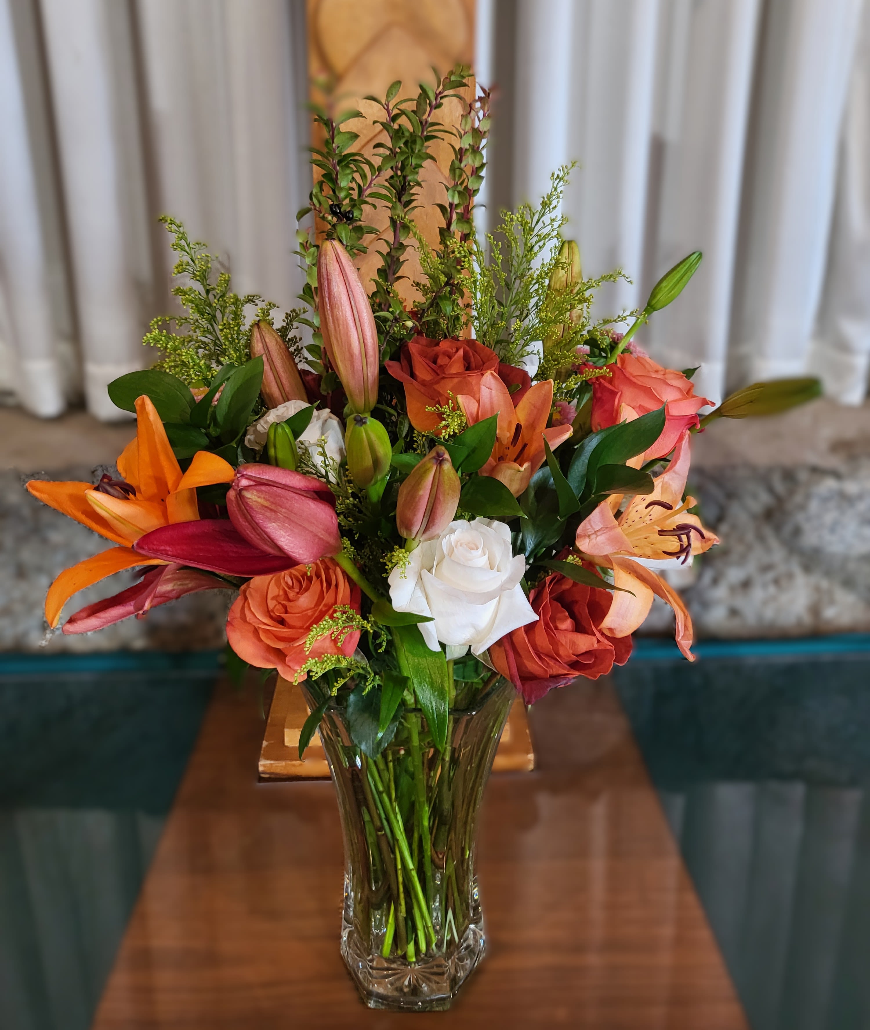 Mixed bouquet of lilies and roses in a clear glass vase