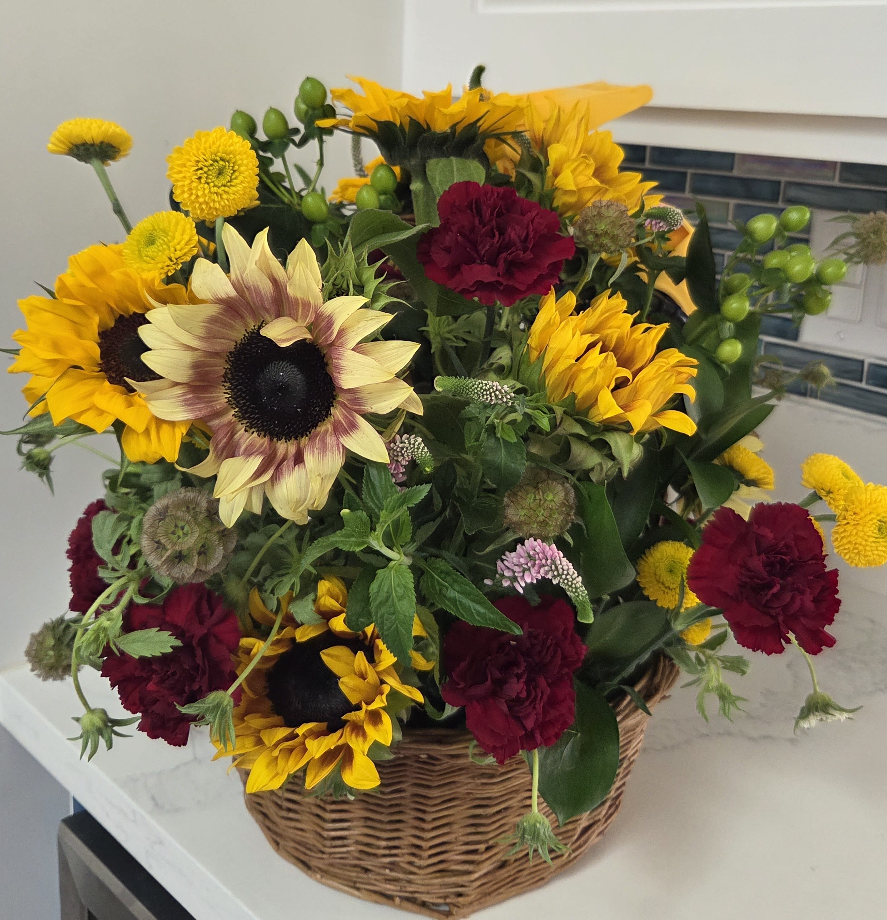 Basket arrangement of sunflowers and burgundy carnations