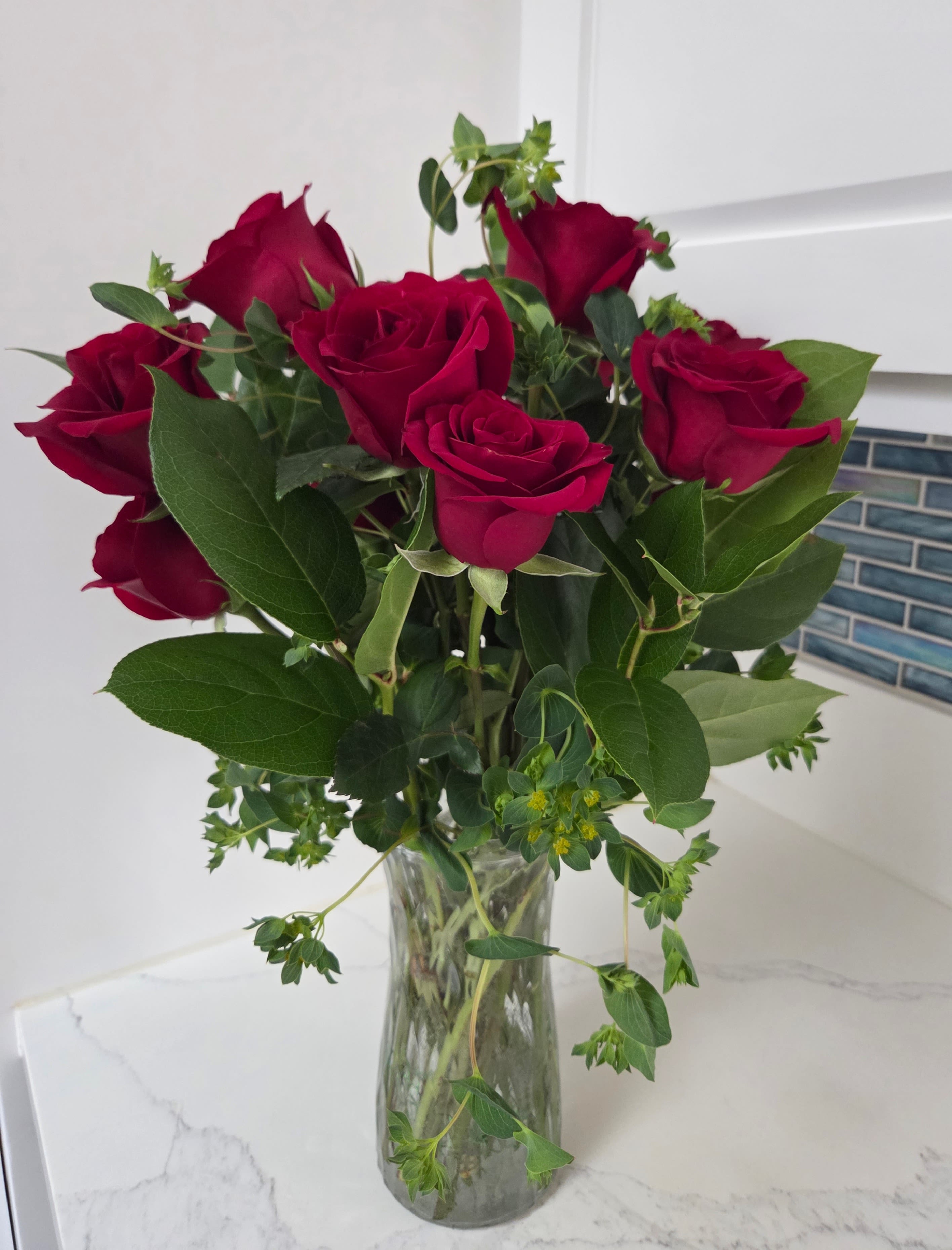 Red Dozen - A classic! Contains one dozen long stemmed red roses and green filler.  Displayed in a clear glass vase.