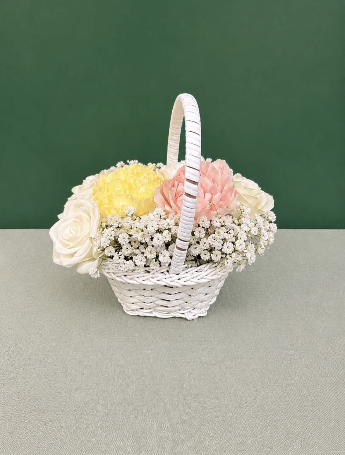 White wicker basket with pastel roses, carnations, and small white filler flowers