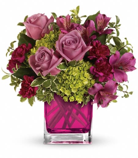 Pink and magenta flowers arranged in a square glass vase