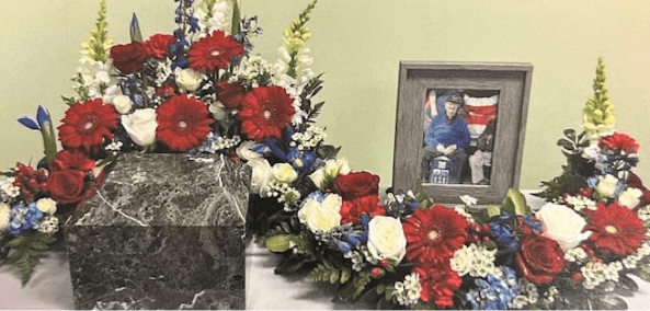 Patriotic Serpentine Urn Wreath S7 - This all Patriotic Serpentine arrangement is designed to wrap around an urn allowing a tribute to be placed in addition to it . Upgrading to Deluxe or Premium will add more flowers to your design. **Ribbon Script is an additional $10