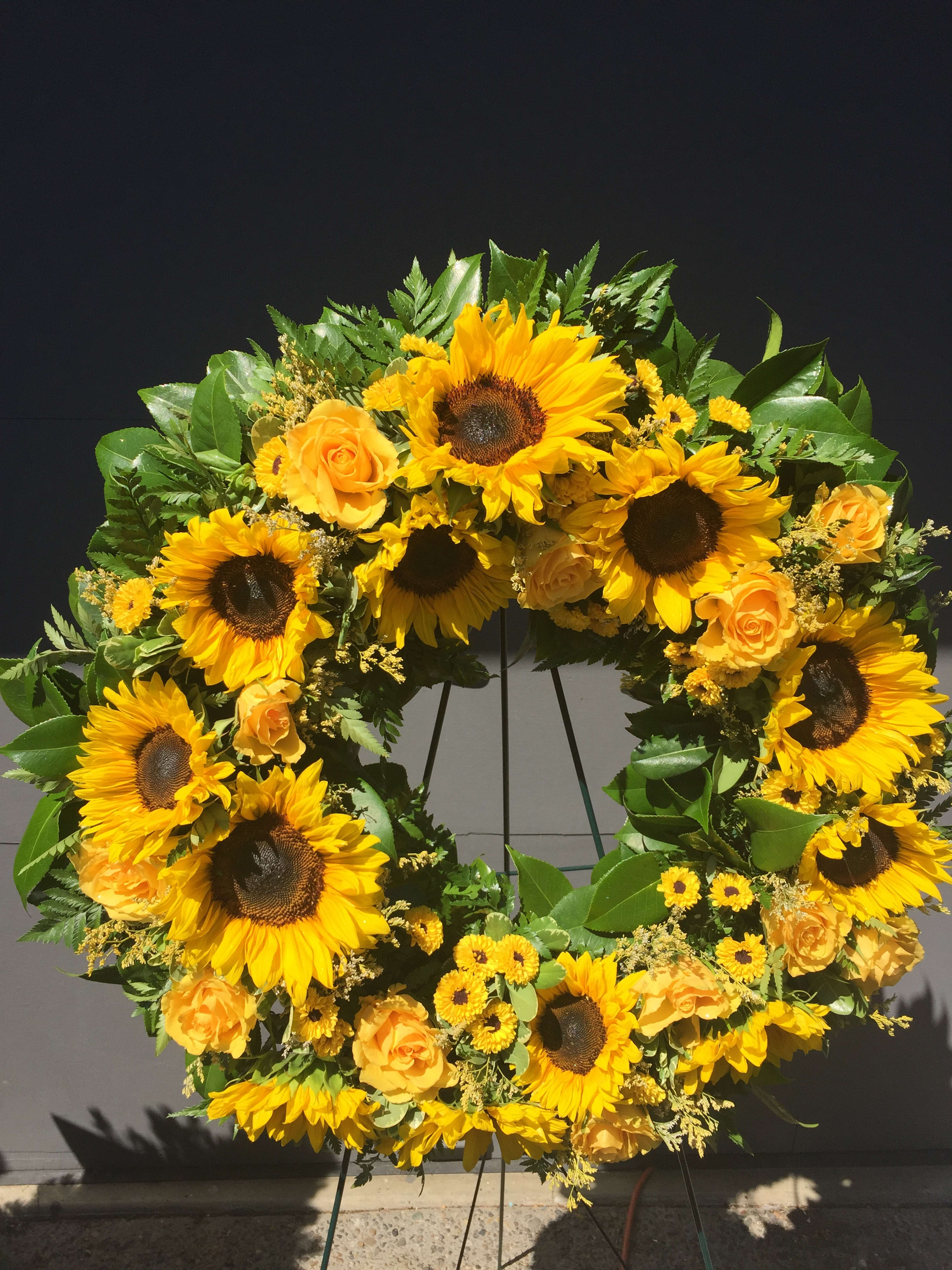 Sunflower and yellow rose wreath on a stand