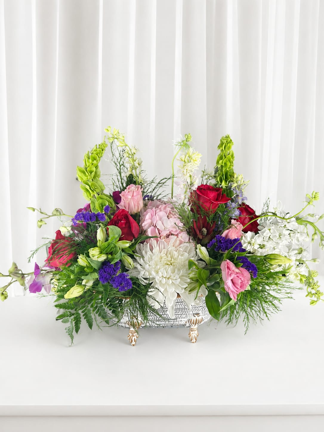 Large mixed floral arrangement in a decorative silver basket