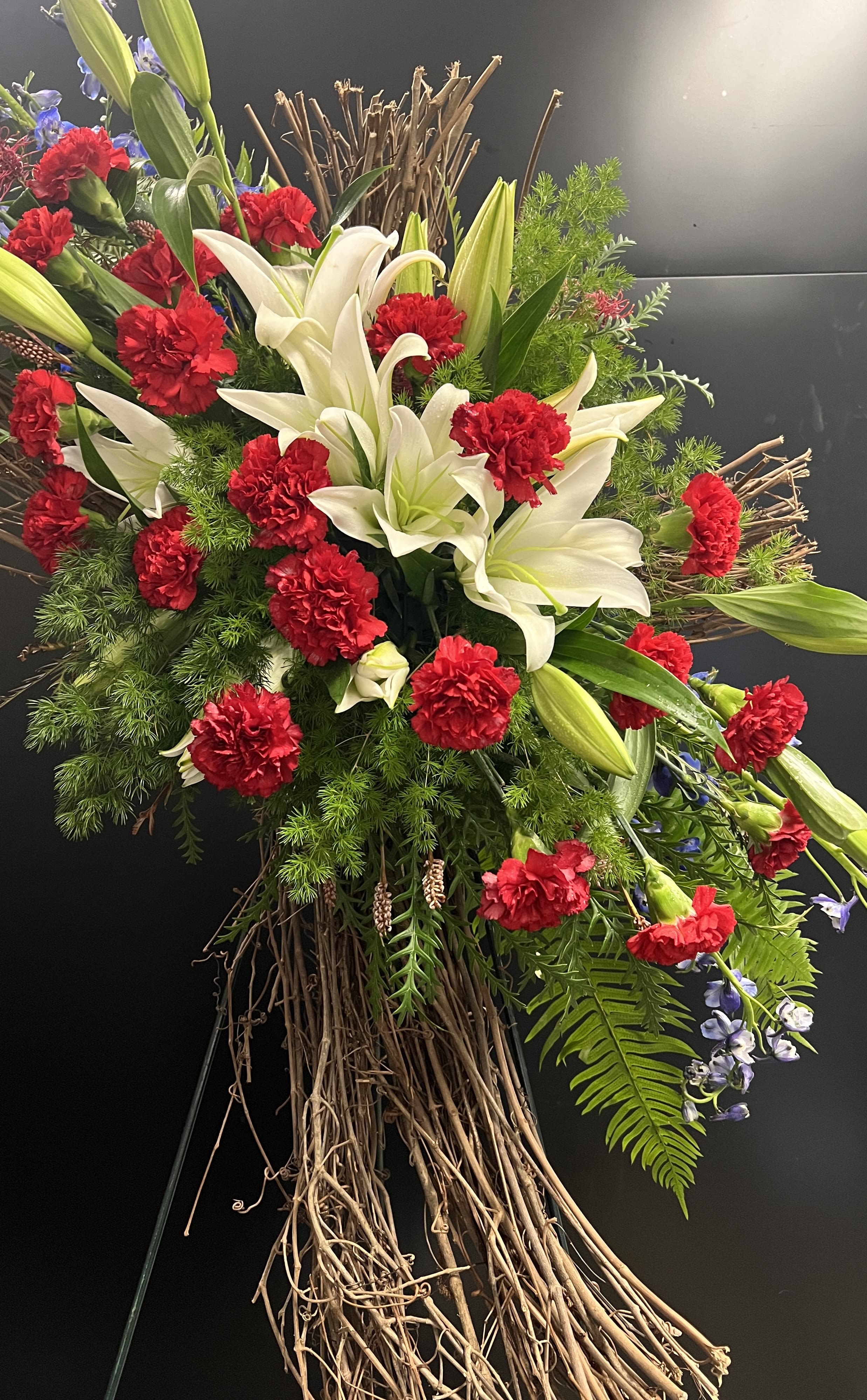 Large floral spray with white lilies and red carnations on a twig base