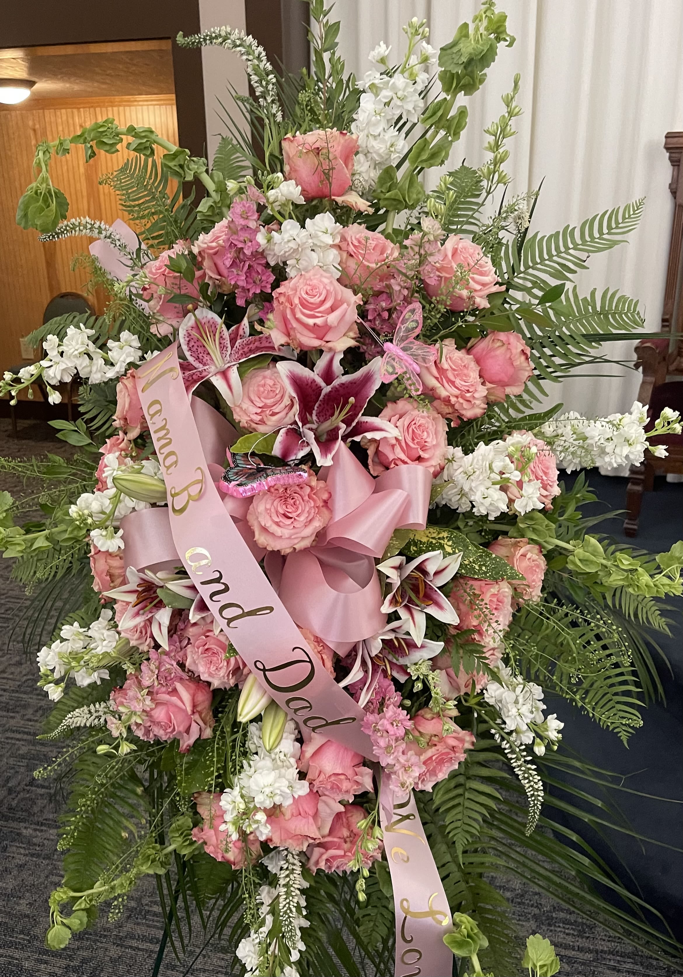 Large pink and white funeral spray with roses and lilies on a stand
