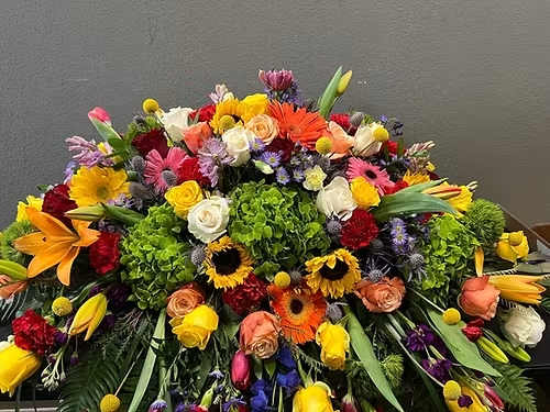 Large colorful floral arrangement with roses, lilies, and gerbera daisies