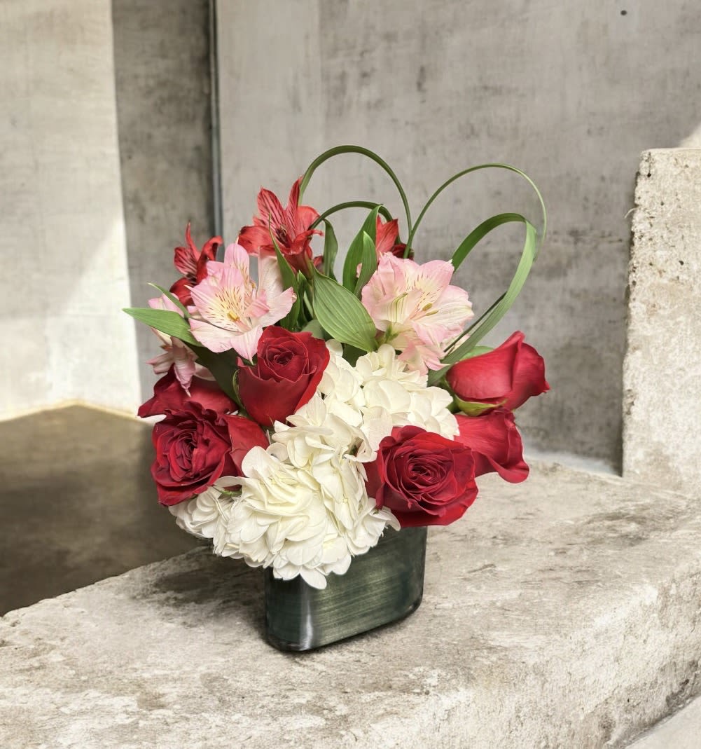Mad For You - Bold yet impeccably refined, Mad For You is the ultimate expression of passion and elegance. Velvety red roses take center stage alongside lush white hydrangea and soft pink alstroemeria, creating a striking contrast that feels both classic and modern for those moments when subtle simply won’t do.  Designed low and compact in a sleek cube vase, this arrangement is perfect for intimate Valentine’s moments, romantic dinners, and grand gestures alike. Mad For You speaks with confidence, depth, and undeniable romance.