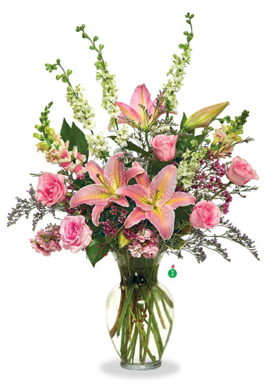 Pink lilies and roses arranged in a clear glass vase