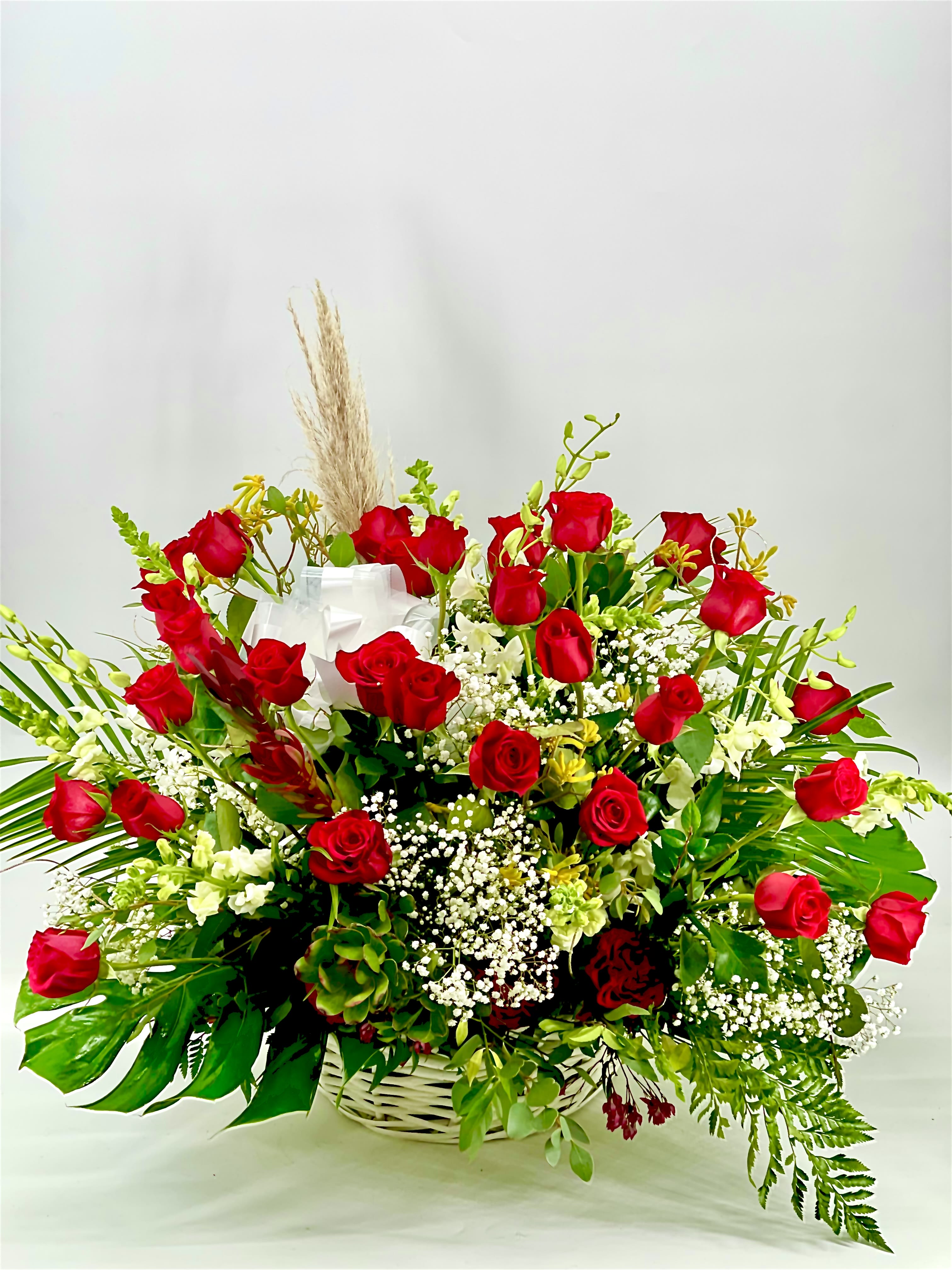 Basket arrangement of red roses with white filler flowers and greenery