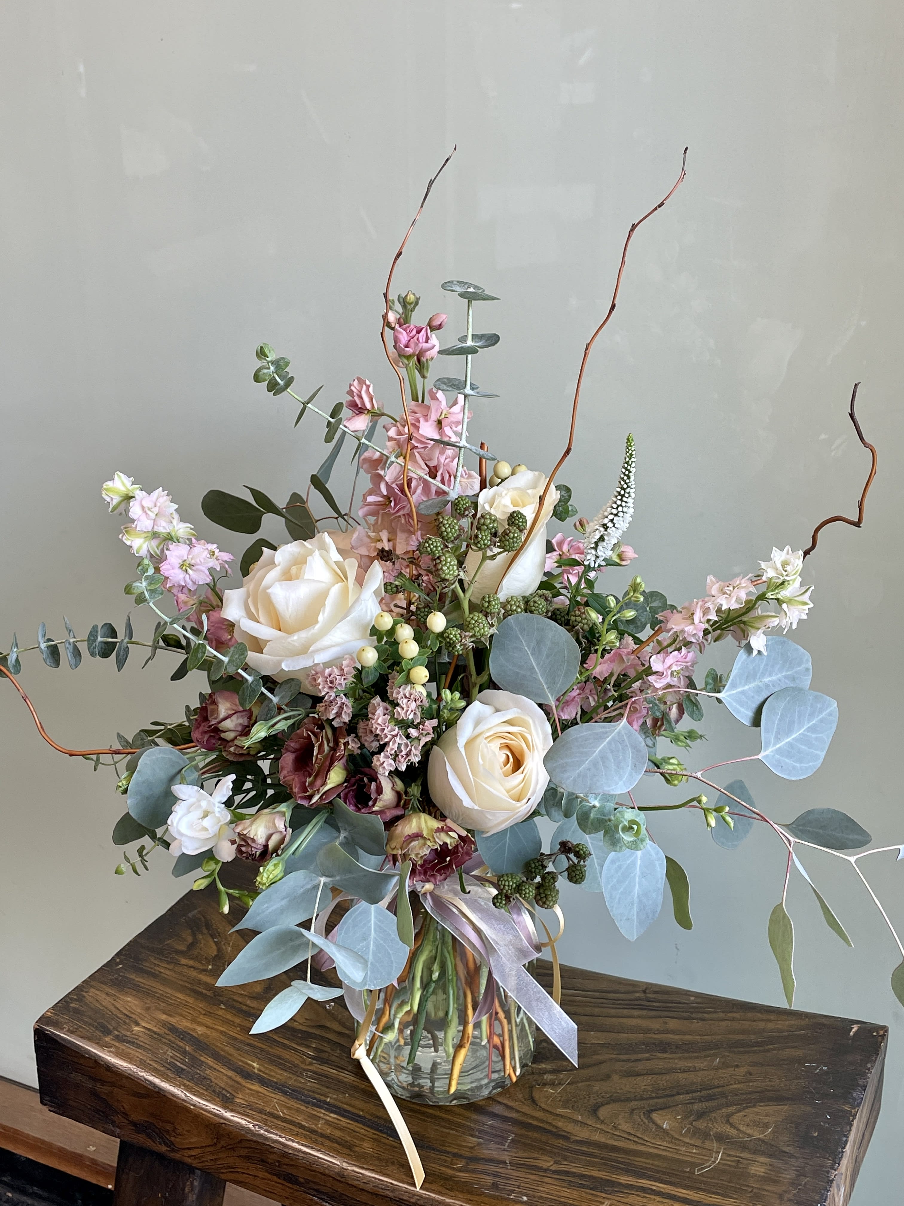 Tall bouquet of cream roses and pink flowers in a glass vase