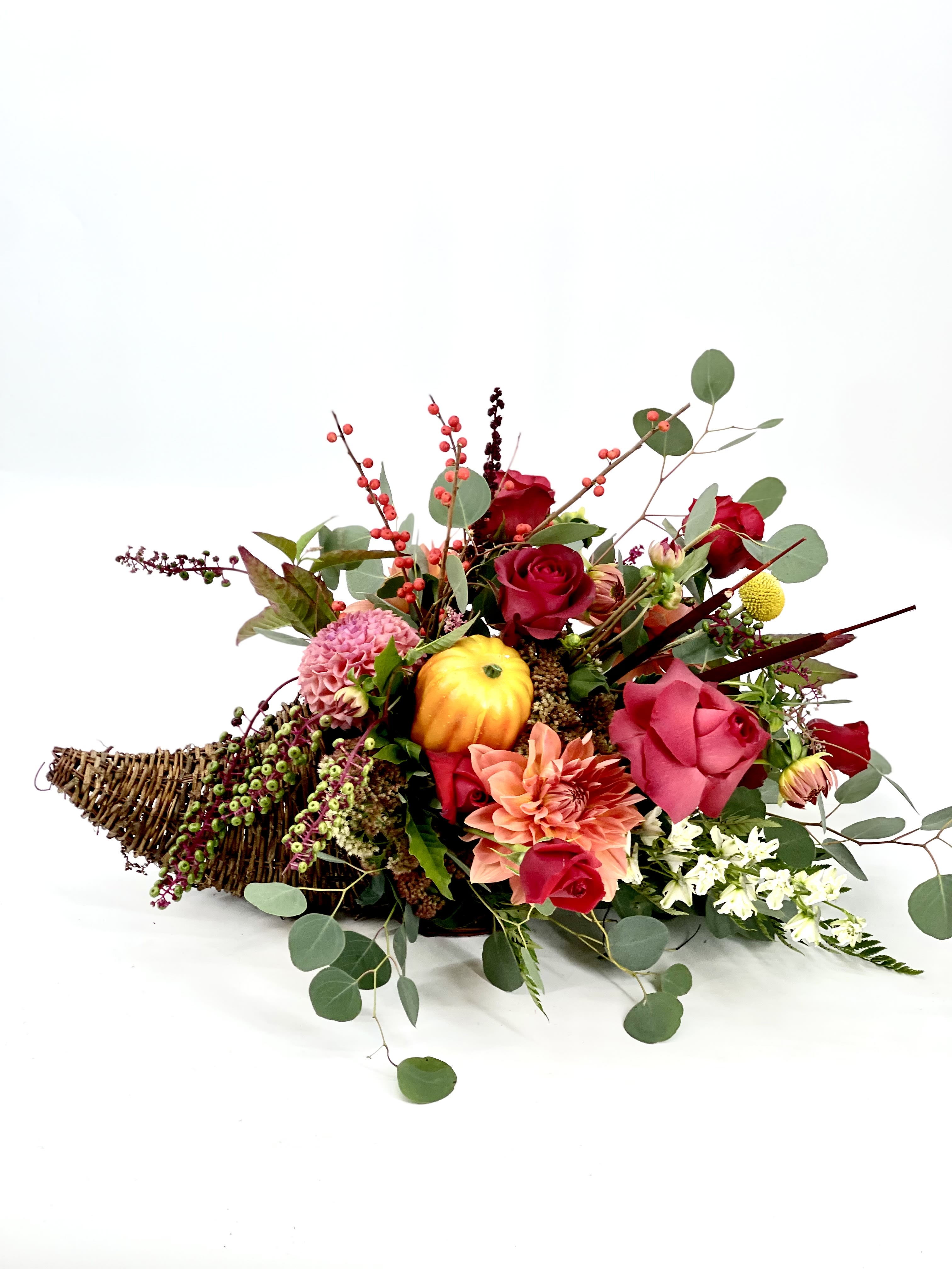 Low floral arrangement with red and pink blooms in a wicker basket